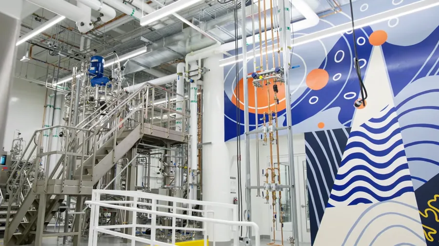 The production suite: cultivators and access stairs on the left, process piping through the centre, the facility mural behind